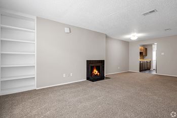 an empty living room with a fireplace and a bookshelf